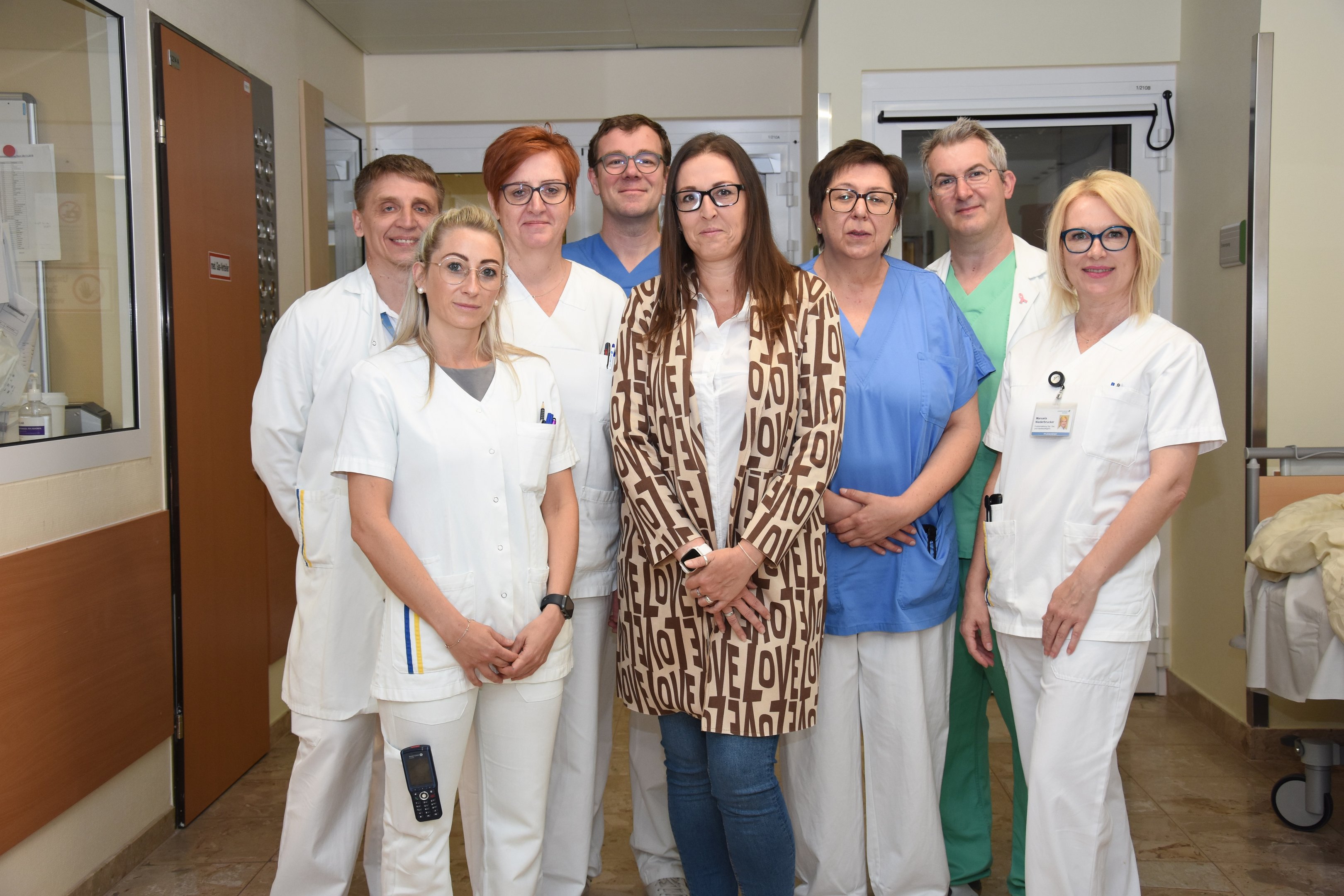 BILDTEXT (v.l.n.r.) vorne: DGKP Anika Bauer (Gyn1 Wochenstation), Patientin Nicole Kopfschlägel, DGKP Martina Fally (Gyn-Ambulanz), DGKP Manuela Niederbrucker (Leitung Allgemeine Ambulanz), Dr. Pavlo Golovanov (Assistenzarzt Anästhesie und Intensivmedizin), DGKP Andrea Straka (Gyn1 Wochenstation) dahinter: Prim Dr. Stefan Palma, MBA DESA FESAIC (Leiter der Abteilung für Anästhesiologie und Intensivmedizin) und Prim. Dr. Catalin Esanu (Leiter der Abteilung für Frauenheilkunde und Geburtshilfe)